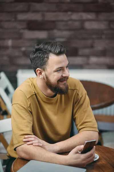 Ung man sitter i café och använder smart telefon. — Stockfoto