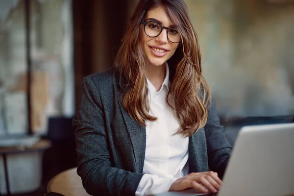 Jovem mulher moderna sentada no café e usando laptop . — Fotografia de Stock