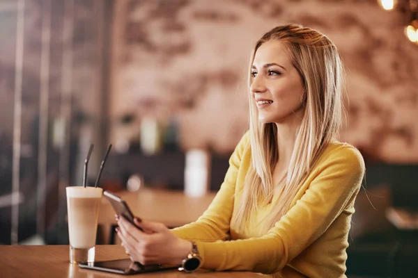 Mulher branca jovem usando tablet enquanto sentado no café e bebendo café . — Fotografia de Stock
