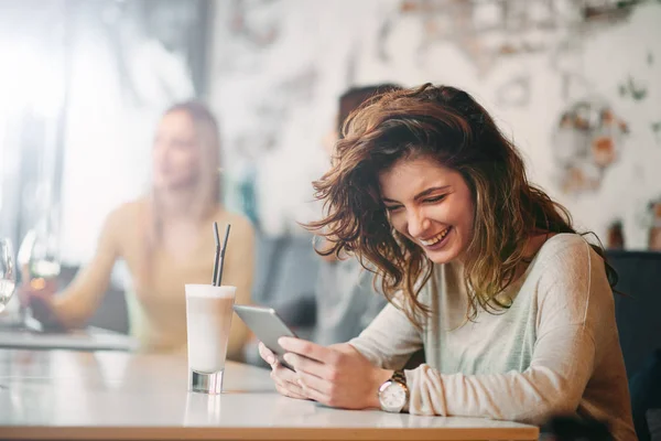 Mujer caucásica joven usando tableta mientras está sentado en la cafetería y beber café . — Foto de Stock