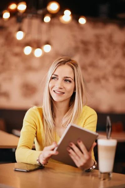 Молодая кавказская женщина, сидя в кафе и попивая кофе, пользуется планшетом . — стоковое фото