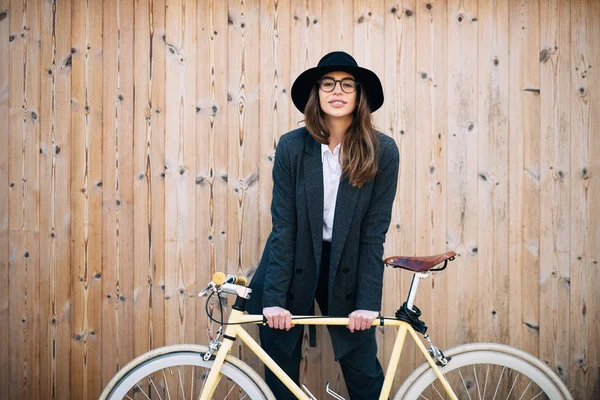 Retrato de una hermosa morena sosteniendo bicicleta. Fondo de madera —  Fotos de Stock