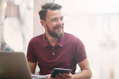 Kafeteryada oturan ve tablet bilgisayarı kullanan genç adam