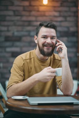 Kafede oturan ve akıllı telefon kullanan genç adam.