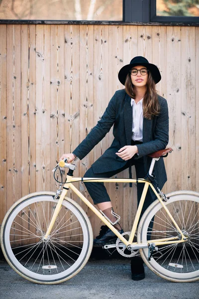 Retrato de una hermosa morena sosteniendo bicicleta. Fondo de madera —  Fotos de Stock