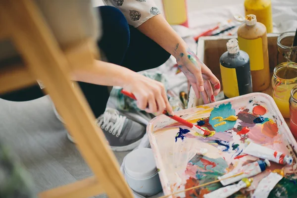 Gros plan des mains de la fille tenant le pinceau et mélangeant les couleurs pour la peinture . — Photo