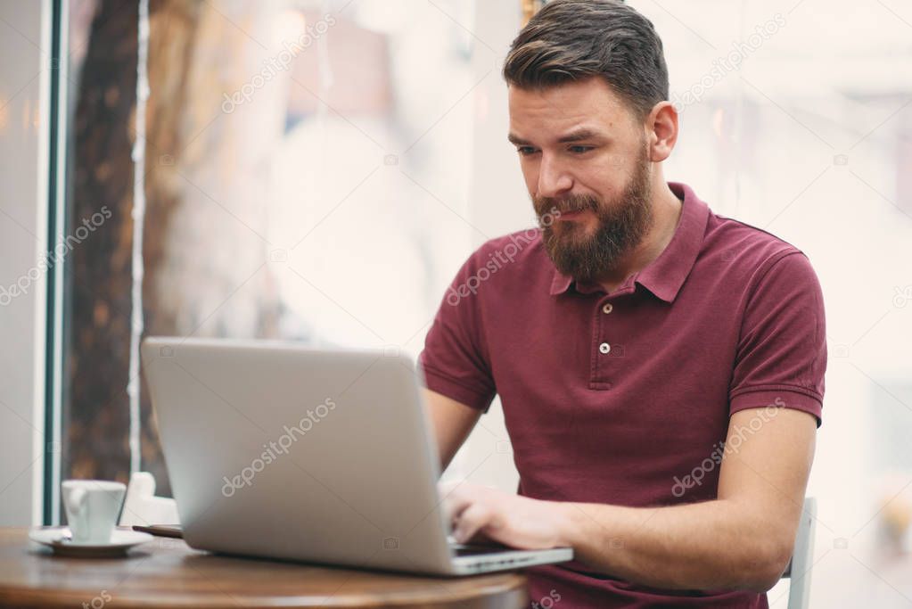 Man sitting in cafe and using laptop for work. 