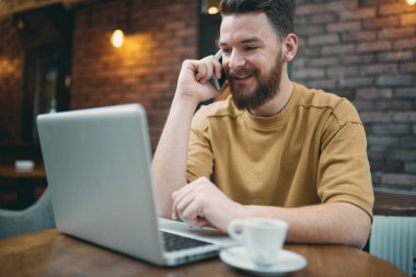 Kafede otururken dizüstü bilgisayar ve akıllı telefon kullanan adam. Yeni teknolojileri kavramı.