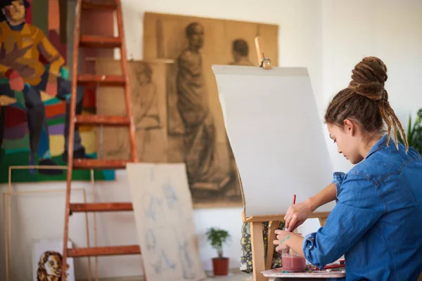 Dziewczyna przygotowuje się do malowanie na sztalugach w atelier. — Zdjęcie stockowe