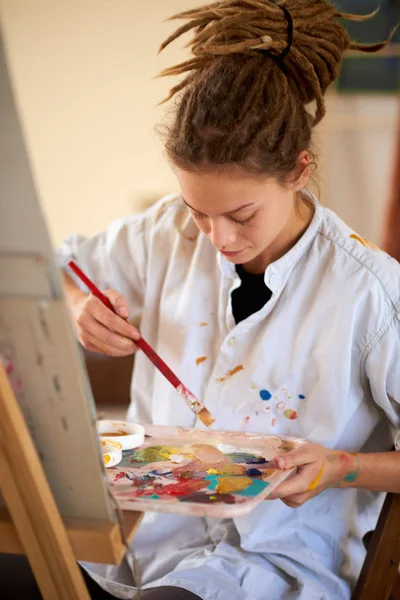 Artistic girl sitting in studio and paint on easel. — Stock Photo, Image