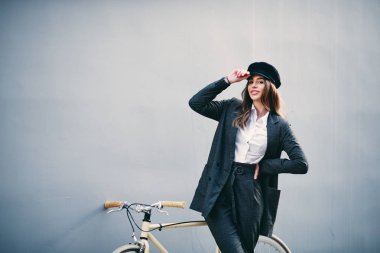 Kadın onun arkasında duvar sarı bisiklet önünde poz... El h