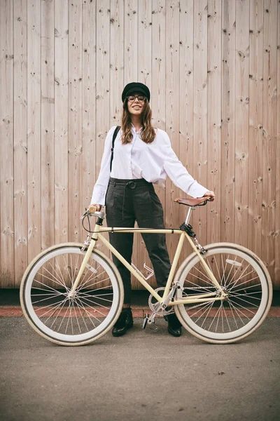 Retrato de una hermosa morena sosteniendo bicicleta. Fondo de madera —  Fotos de Stock