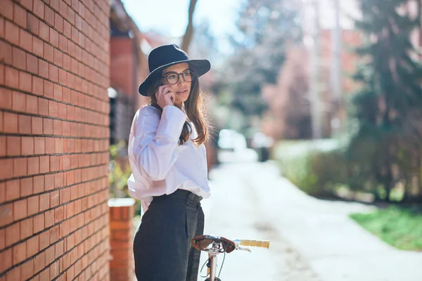 Mujer usando el teléfono inteligente y sosteniendo la bicicleta mientras está de pie en th —  Fotos de Stock