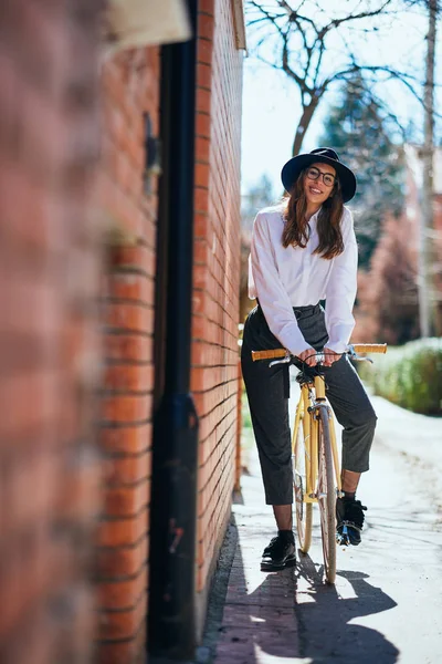 Mujer posando en la bicicleta. Junto a su pared de ladrillo . —  Fotos de Stock