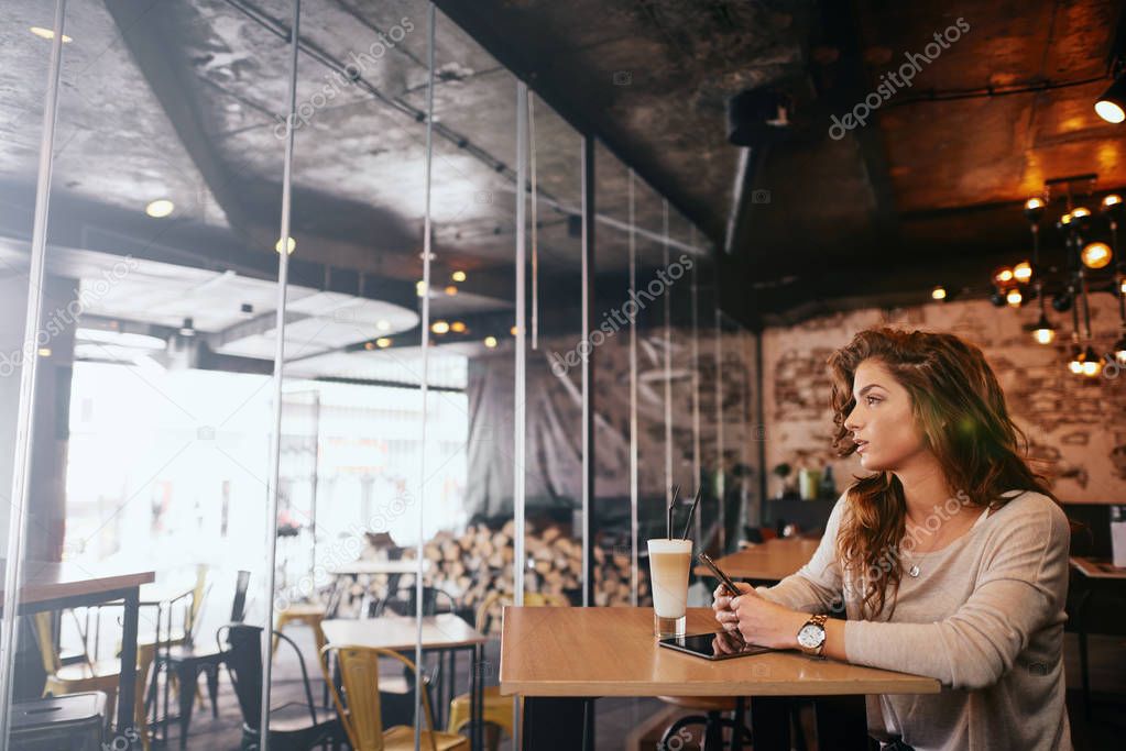 Yung woman sitting in cafe and drinking coffee.