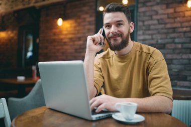 Kafede oturan ve akıllı telefon kullanan genç adam.