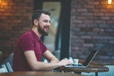 Kafede oturan ve dizüstü bilgisayar kullanarak genç adam.