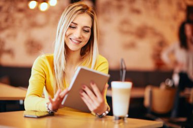 Beyaz kadın tablet kafede oturan ve kahve içme kullanma.