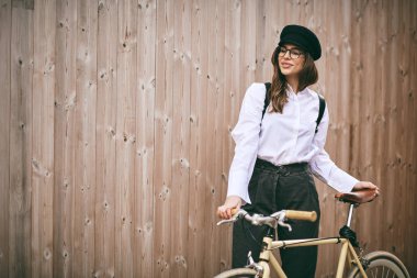 Güzel esmer holding Bisiklet portresi. Ahşap arka plan.