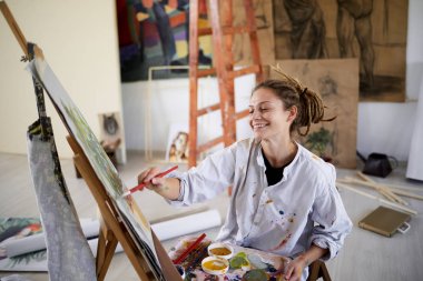 Sanatsal kız oturan stüdyo ve boya şövale üzerinde.