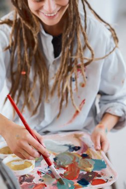 Sanatsal kız oturan stüdyo ve boya şövale üzerinde.