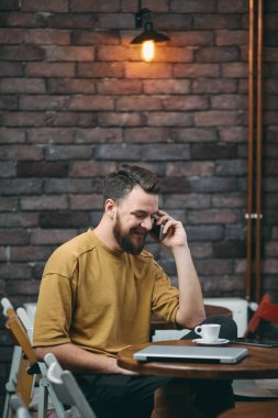 Kafede otururken dizüstü bilgisayar ve akıllı telefon kullanan adam. Yeni teknolojileri kavramı