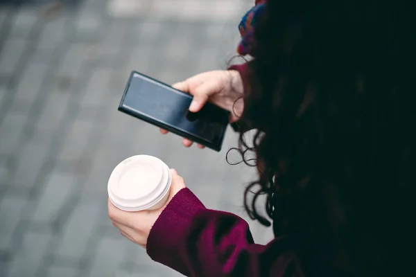 用智能手机关闭女孩的手发短信和拿着咖啡去 专注于咖啡杯 — 图库照片