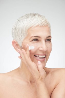 Kremayı koyarak güzel kadın kıdemli baş shot.