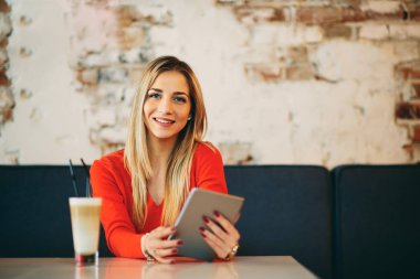 Beyaz kadın tablet kafede oturan ve kahve içme kullanma.