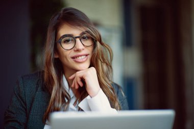 Kafede oturan ve dizüstü bilgisayar kullanarak genç modern kadın.