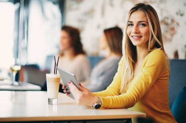 Beyaz kadın tablet kafede oturan ve kahve içme kullanma.