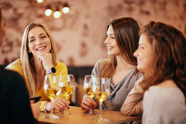 Amigos do sexo feminino bebendo vinho e conversando enquanto sentados no bar . — Fotografia de Stock