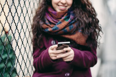Kadının'ın el çit açık havada üzerinde otururken akıllı telefon tutarak yakın çekim.