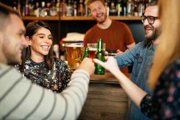 Przyjaciele stojący w barze i wznoszący toast piwem. — Zdjęcie stockowe