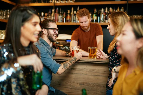 Un gruppo di amici che beve birra, chiacchiera e si diverte al pub. Notte fuori . — Foto Stock