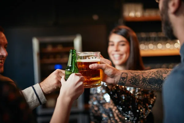 Vrienden staan in de bar en toasten met bier. — Stockfoto