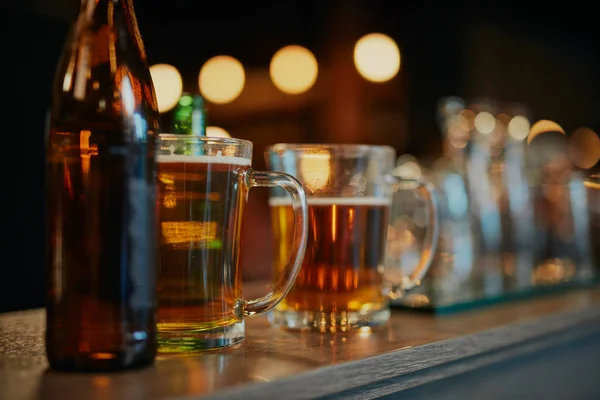 병에 든 상쾌 한 맥주와 막대 카운터 위에 놓인 파인트짜리 맥주 그림. 술집 내부. — 스톡 사진