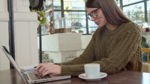 Приваблива Біла Брюнетка Светрі Окулярах Сидячи Кафе Друкуючи Ноутбуці — стокове відео