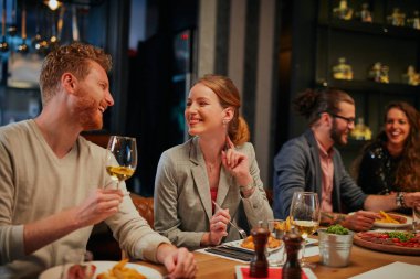 Group of best friends sitting in restaurant, having dinner, drinking wine and having fun. clipart