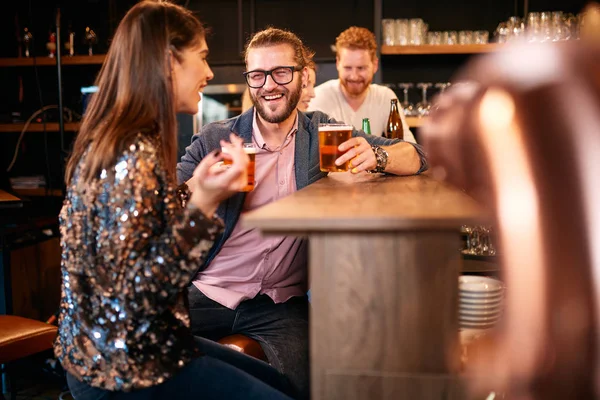 Eine kleine Gruppe von Freunden sitzt in einem irischen Pub an der Theke, trinkt Bier und plaudert. Nachtleben. — Stockfoto