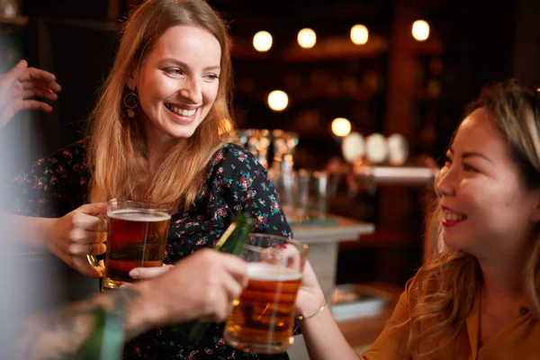 Vrienden staan in de bar en toasten met bier. — Stockfoto