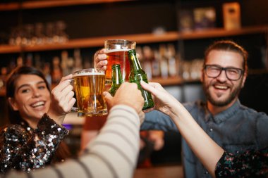 Arkadaşlar barda durup birayla kadeh kaldırıyorlar..