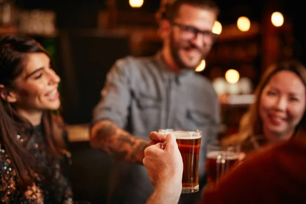 Vrienden staan in de bar en toasten met bier. — Stockfoto