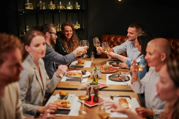 Skupina nejlepších přátel sedí v restauraci, večeří, popíjí víno a baví. — Stock fotografie