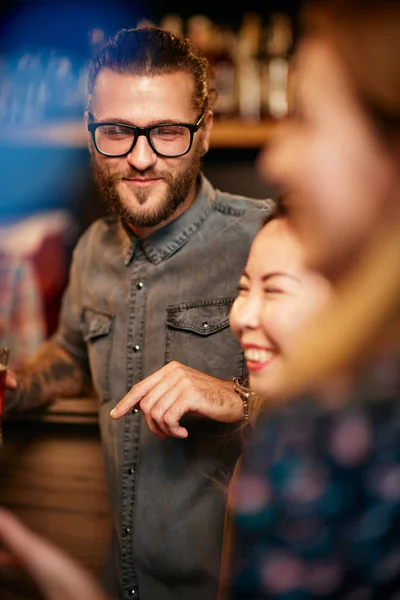 Aantrekkelijke blanke man met een baard en een bril die op het aanrecht leunt en bier vasthoudt. — Stockfoto