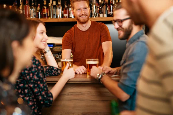 Grupo de amigos bebiendo cerveza, charlando y divirtiéndose en el pub. Noche fuera. . — Foto de Stock