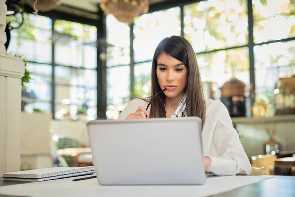 Bonita mulher de negócios branca elegante sentado no café, segurando óculos e usando laptop . — Fotografia de Stock