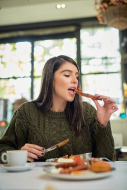 Çekici esmer, sabah restoranda oturmuş kahvaltı yapıyor..