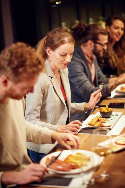 Группа друзей, сидящих в retaurant и едят ужин
. 