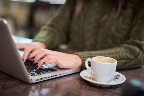 Κοντινό πλάνο του καυκάσιου ελεύθερου επαγγελματία με πουλόβερ που κάθεται στο καφέ και πληκτρολογεί στο laptop. Στο τραπέζι δίπλα στο λάπτοπ είναι ο καφές.. — Φωτογραφία Αρχείου